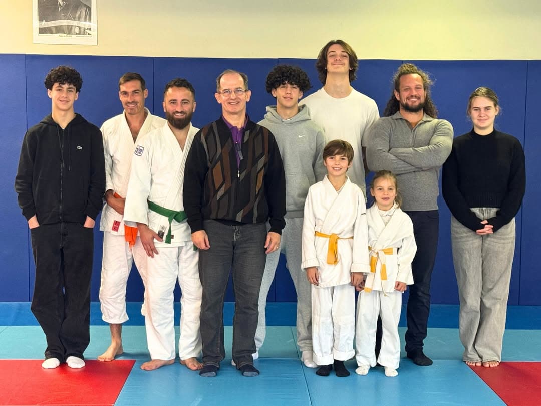 Le coach entouré du groupe d’athlètes et de jeunes judokas sur les tatamis du dojo